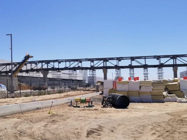 Long steel truss structure over a site with stacked materials