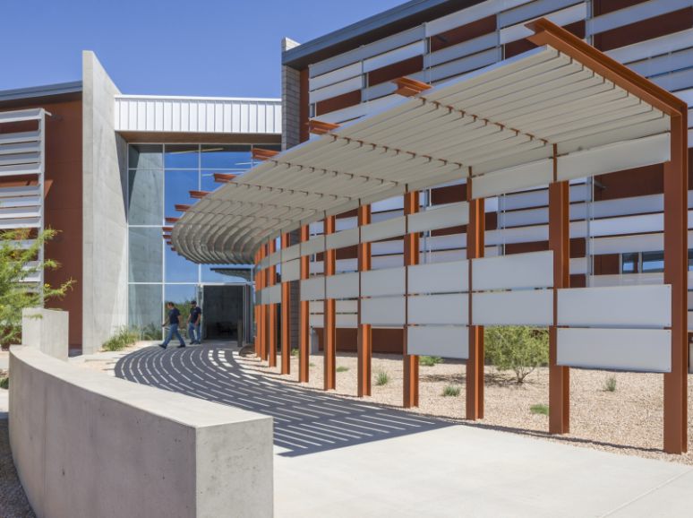 Building entrance with a steel sunshade on red columns