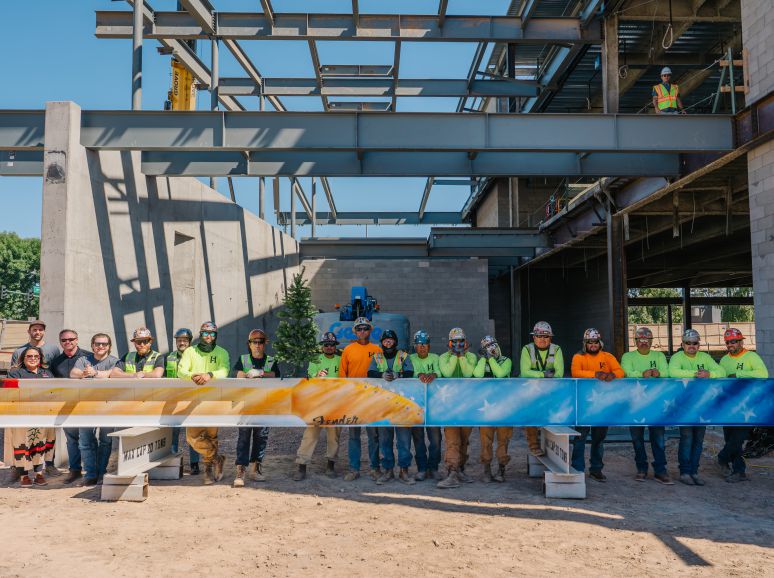 Crew standing behind a painted steel beam on a job site