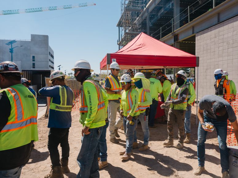 Crew in hard hats and safety vests gathered on a job site