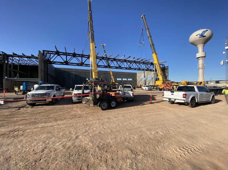 Cranes and trucks on a site with a steel frame going up